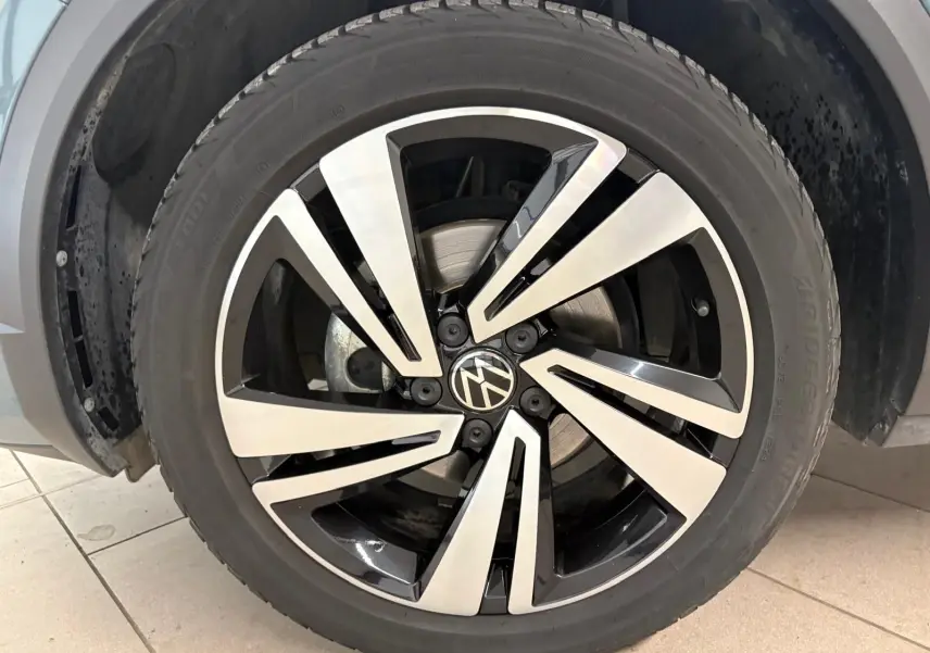 Gros plan sur la jante alliage bicolore du Volkswagen T-Roc 2024, version R-Line, avec logo VW au centre.