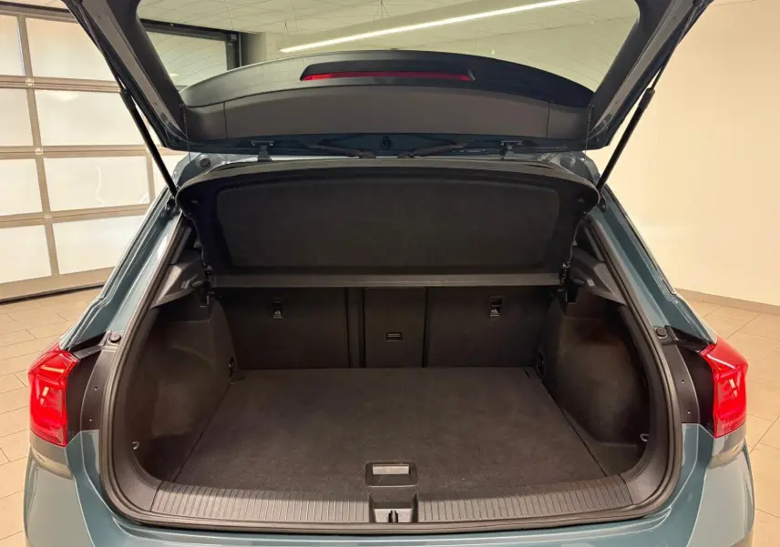 Coffre ouvert du Volkswagen T-Roc 2024 bleu pétrole vu de l'arrière, montrant un espace de chargement spacieux et propre.