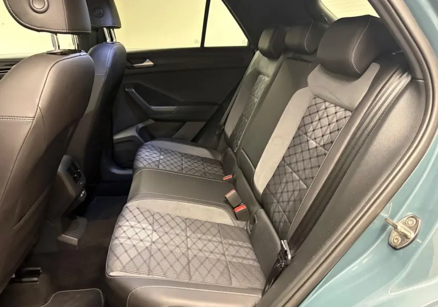 Vue côté droit de l'intérieur arrière du Volkswagen T-Roc 2024 bleu pétrole avec sièges en cuir et tissu à motifs géométriques.