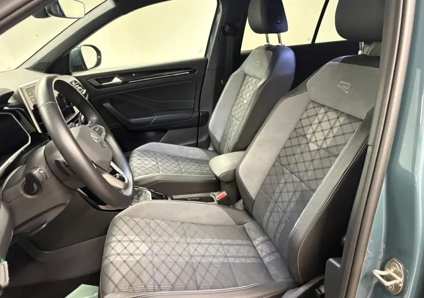 Vue intérieure côté conducteur du Volkswagen T-ROC 1.5 TSI R-Line 2024 avec sièges en tissu et cuir gris à motifs géométriques