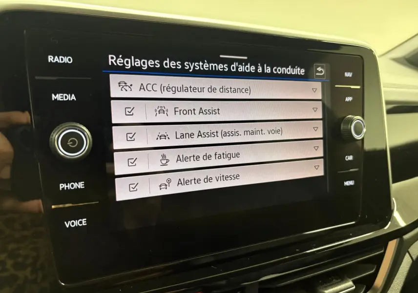 Écran tactile du système d'infodivertissement du Volkswagen T-Roc 2024 affichant les réglages d'aide à la conduite.
