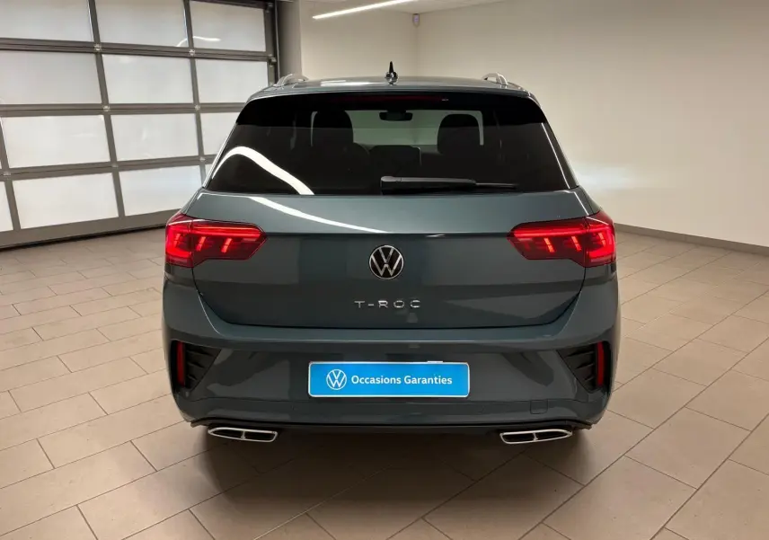 Vue arrière d'un Volkswagen T-Roc 2024 bleu pétrole avec feux LED allumés et double sortie d'échappement rectangulaire.
