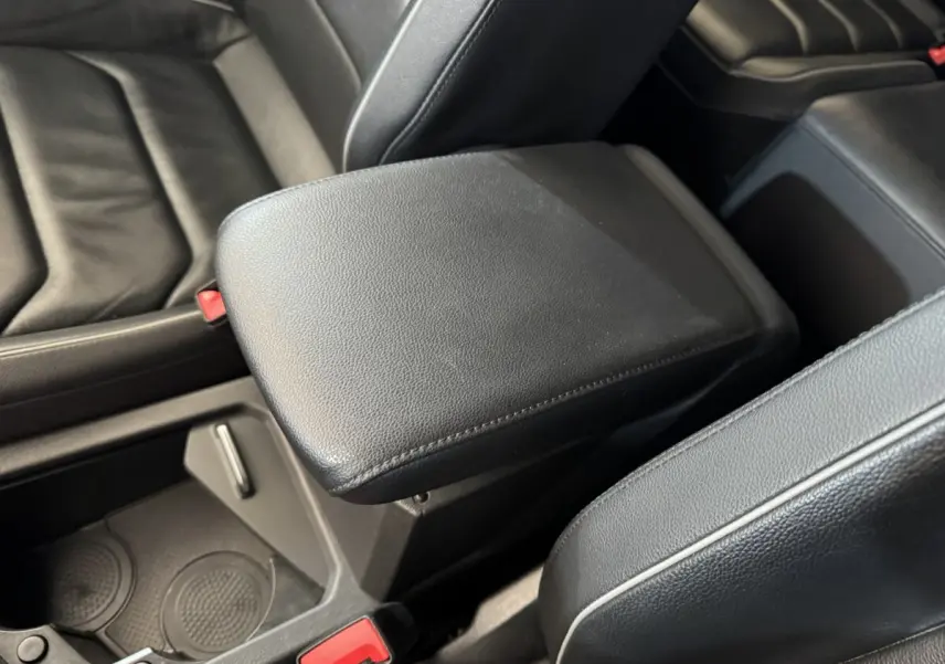Gros plan sur l'accoudoir central noir en cuir entre les sièges avant du Volkswagen Tiguan Allspace gris foncé.