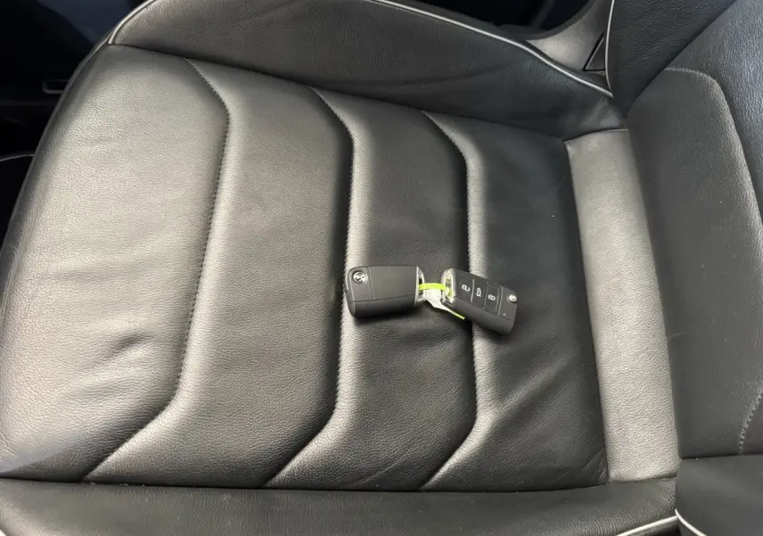 Gros plan sur la clé Volkswagen posée sur le siège en cuir noir côté conducteur du Tiguan Allspace gris foncé.