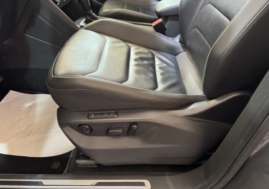 Gros plan sur le siège conducteur en cuir noir du Volkswagen Tiguan Allspace 2019, avec commandes électriques visibles.