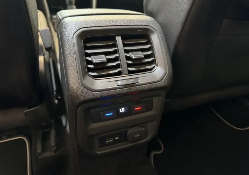 Détail de la console arrière avec bouches d’aération, commandes climatisation et prises USB et 12V du Volkswagen Tiguan Allspace gris foncé.