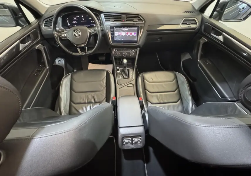 Vue intérieure avant du Volkswagen Tiguan Allspace 2019, sièges cuir noirs et écran tactile central visible.