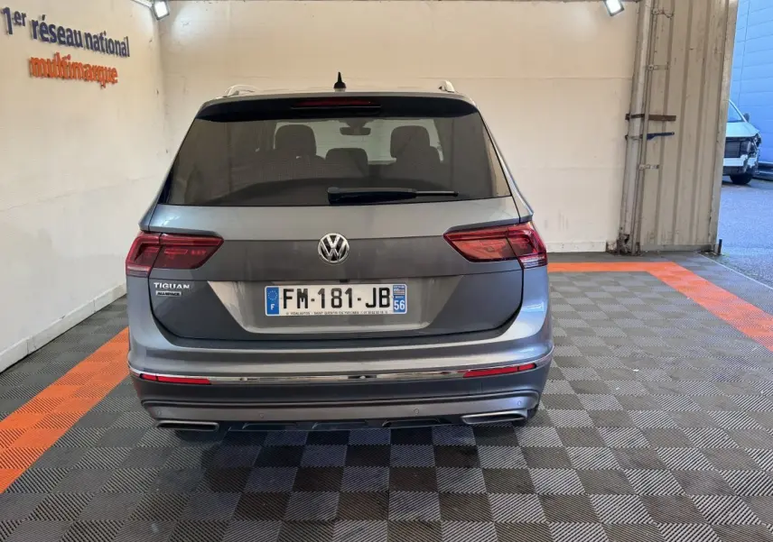 Vue arrière d'un Volkswagen Tiguan Allspace gris foncé stationné en intérieur sur un sol à damiers noir et orange.