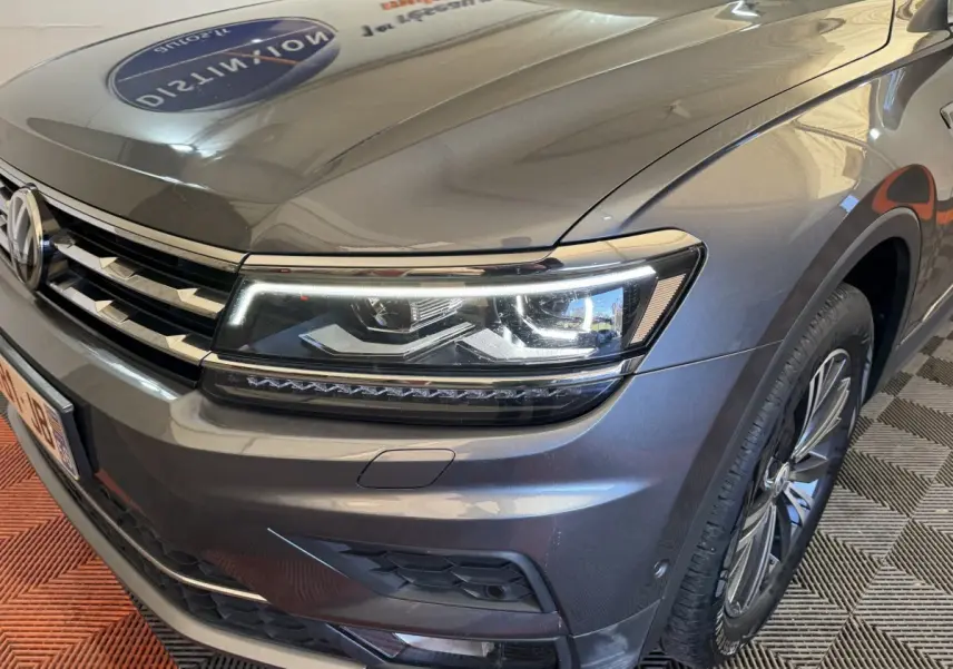 Vue 3/4 avant droit d’un Volkswagen Tiguan Allspace gris foncé avec phares LED et jantes alliage visibles.