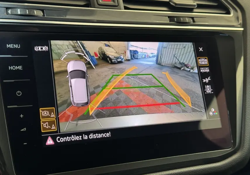 Vue écran multimédia du Volkswagen Tiguan Allspace gris foncé en marche arrière avec caméra de recul et guidage de trajectoire.