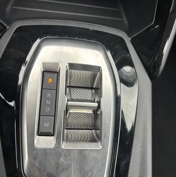 Gros plan sur la console centrale de la Peugeot 208 Hybrid 100 e-DCS6 Style 2025 gris, montrant la commande de boîte auto et les boutons de sélection.