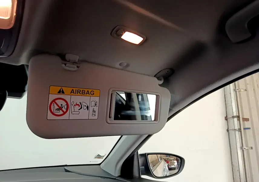 Vue intérieure du pare-soleil côté conducteur gris clair avec miroir et avertissement airbag sur Hyundai i20 2022.