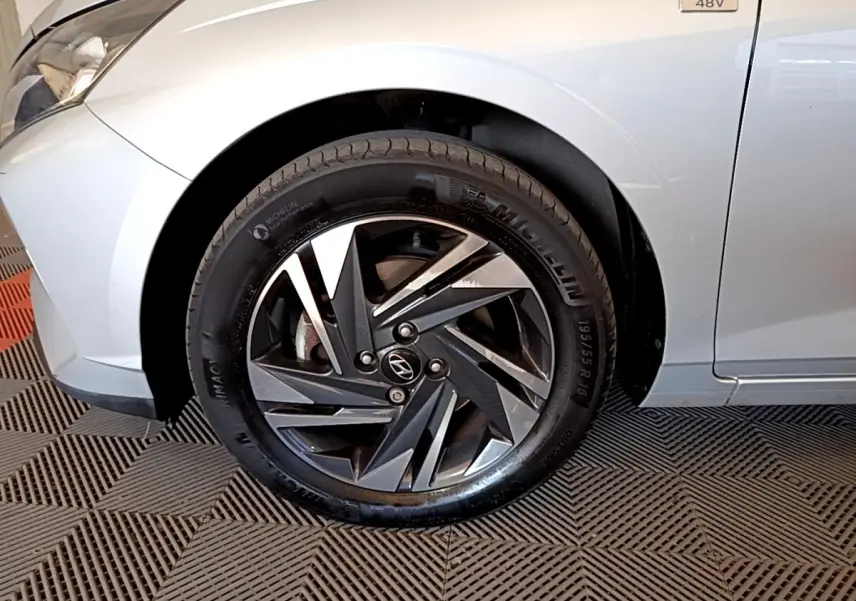Gros plan sur la roue avant gauche de la Hyundai i20 gris clair avec jante alliage et badge 48V visible sur l'aile.