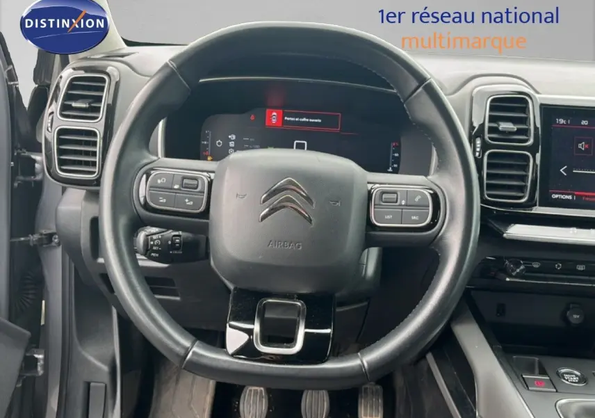 Vue frontale du volant noir et du tableau de bord numérique d’un Citroën C5 Aircross gris clair métal de 2020.