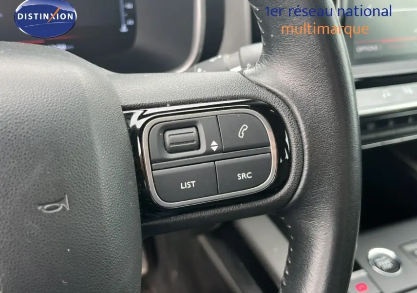 Gros plan sur les commandes au volant côté gauche du Citroën C5 Aircross gris clair métal, version PureTech 130ch Feel.