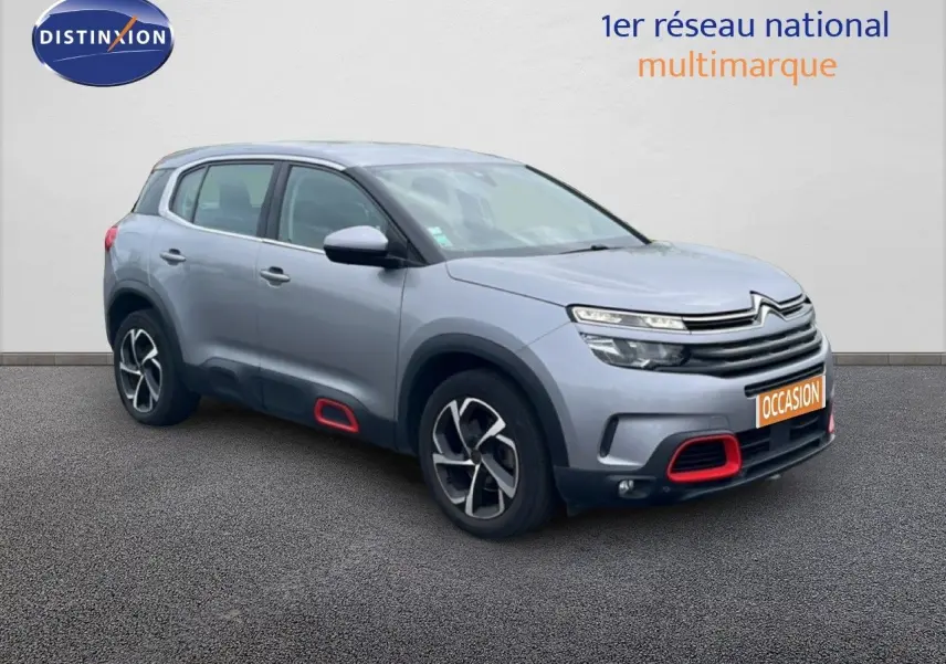 Citroën C5 Aircross gris clair métal en 3/4 avant droit avec détails rouges sur boucliers et bas de caisse.