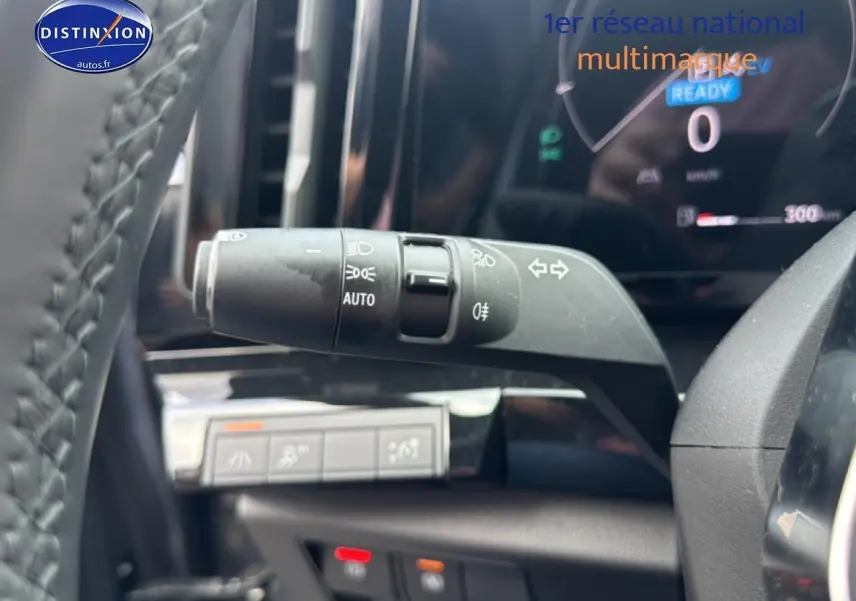 Gros plan sur la commande des phares automatiques dans l’habitacle gris du Renault Austral 2024 hybride.