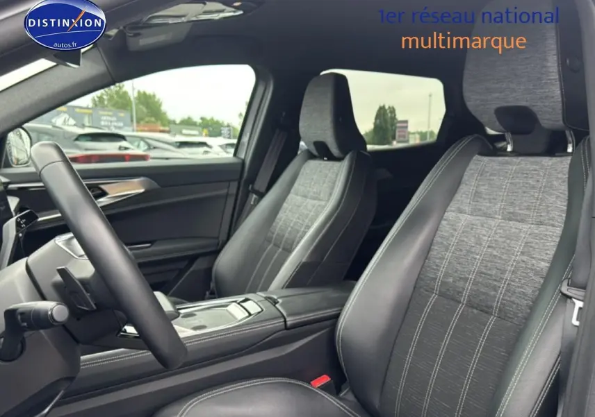 Vue intérieure côté conducteur du Renault Austral 2024, sièges gris tissu et cuir avec accoudoir central noir.