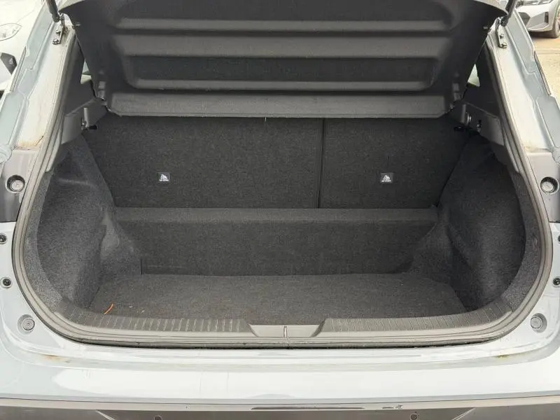 Coffre ouvert vu de l'arrière du Nissan Qashqai 1.3 Mild Hybrid gris Argile, intérieur noir et tapis de sol.