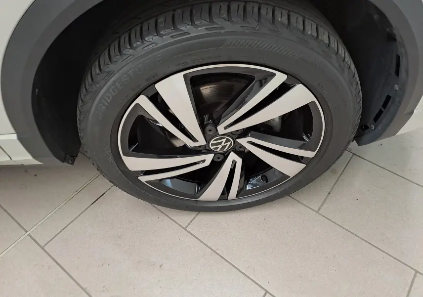 Gros plan sur la roue avant gauche du Volkswagen T-Roc 2024 Gris Ascot avec jante alliage bicolore au design dynamique.