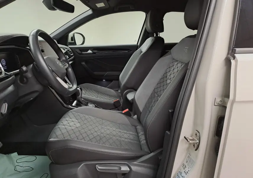 Vue intérieure côté conducteur du Volkswagen T-Roc 2024 avec sièges R-Line en tissu gris à motif losanges.