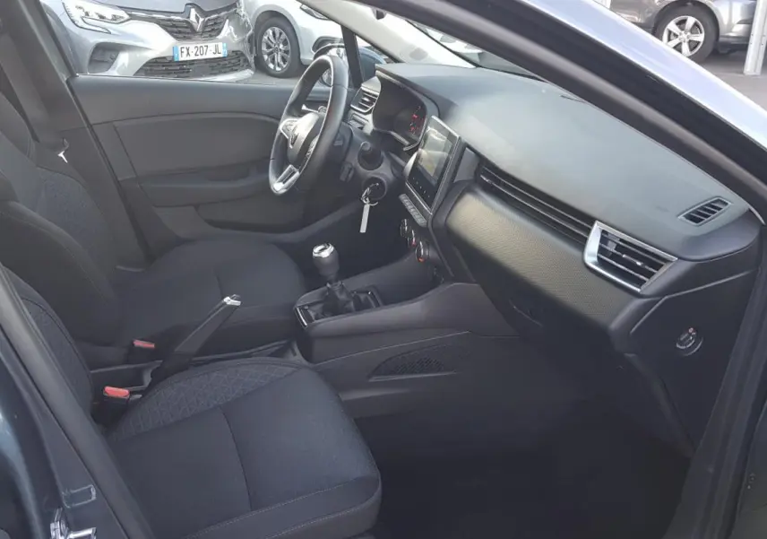 Intérieur de la Renault Clio gris 2021, vue côté conducteur montrant sièges noirs et tableau de bord moderne.