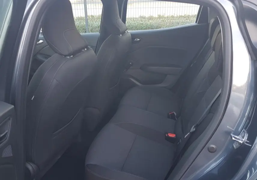 Vue intérieure côté arrière droit d'une Renault Clio gris, montrant les sièges arrière en tissu noir.