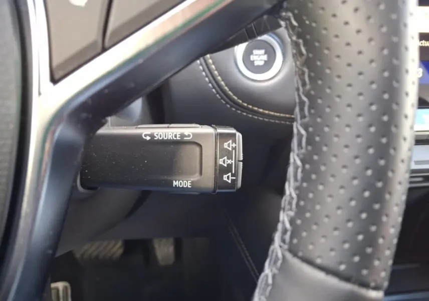 Gros plan sur la commande multifonction noire côté gauche du volant perforé du Renault Symbioz noir, avec bouton démarrage visible.