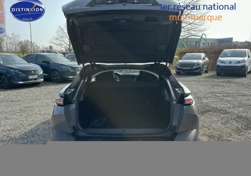 Vue arrière d'une Peugeot 408 Hybrid 145 allure gris sélénite avec coffre ouvert, montrant l'espace de chargement.