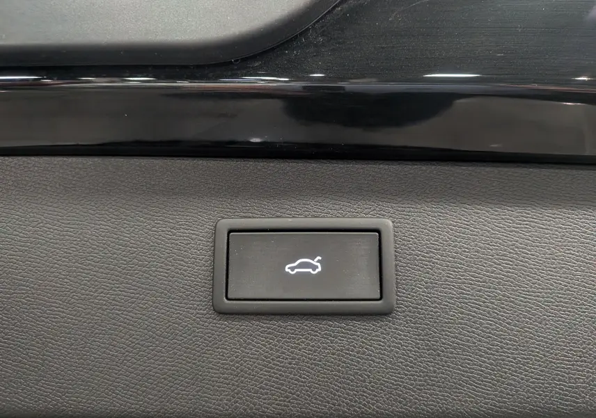 Bouton intérieur noir avec symbole blanc d'ouverture de coffre, sur tableau de bord noir brillant du CUPRA Formentor eHybrid 2025.