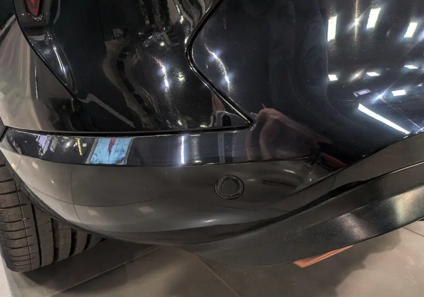 Détail du pare-chocs arrière droit noir minuit du CUPRA Formentor eHybrid 2025 avec capteur de stationnement intégré.