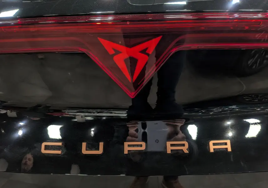Gros plan sur le logo rouge et l'inscription CUPRA en bronze sur la malle arrière noire Minuit du Formentor eHybrid 2025.