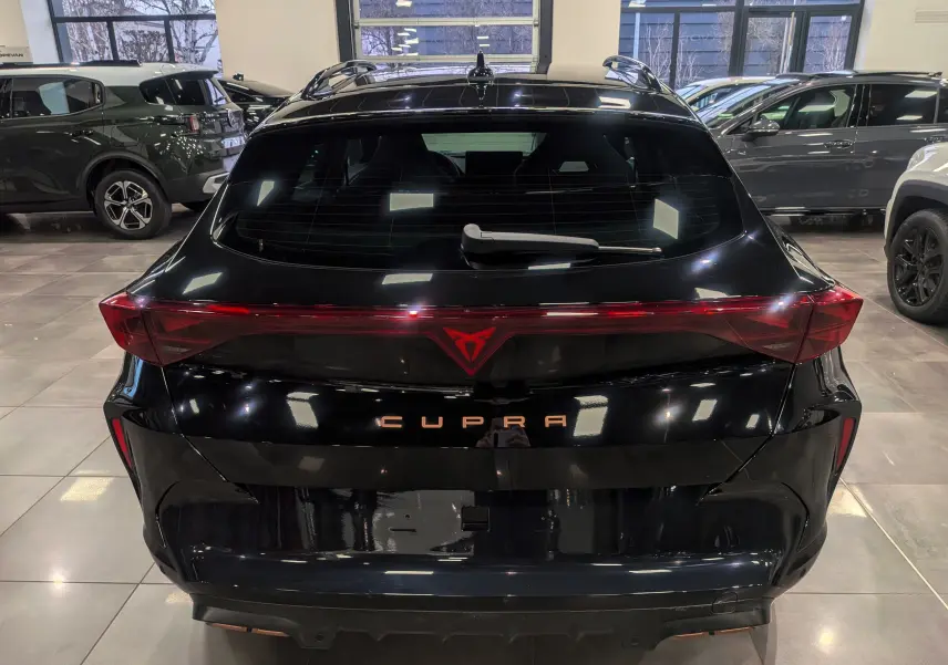Vue arrière d'une CUPRA Formentor eHybrid 2025 en noir minuit, avec feux arrière reliés et logo CUPRA lumineux.