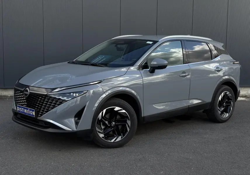 Nissan Qashqai 2025 gris Ceramic en 3/4 avant droit, avec jantes alliage noires et calandre distinctive.