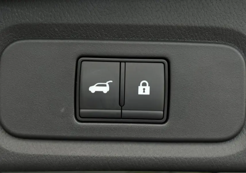 Gros plan sur les boutons de hayon électrique et de verrouillage intérieur, tableau de bord noir du Nissan Qashqai gris Ceramic.