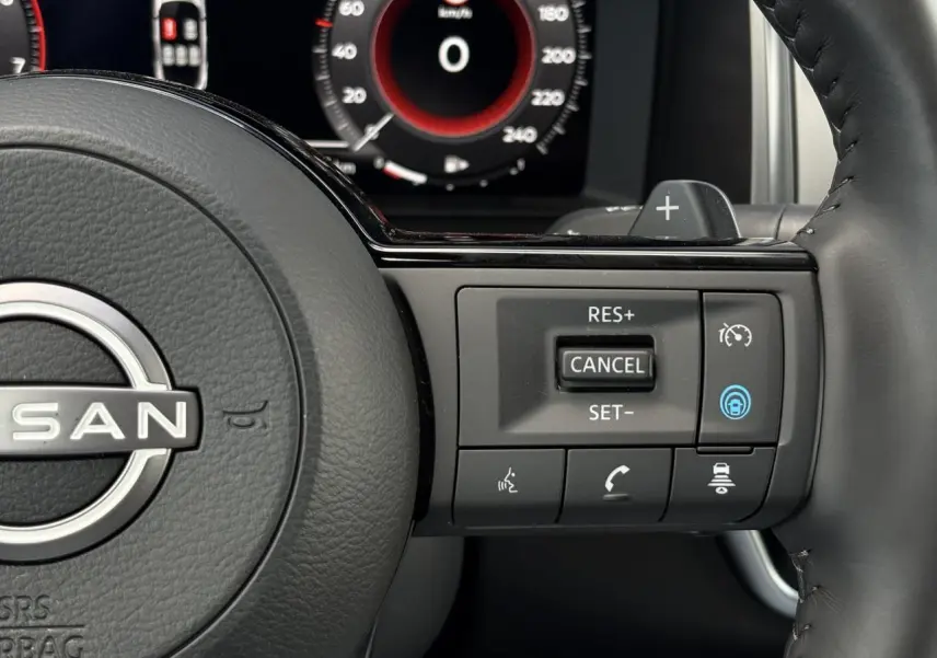 Gros plan sur le volant cuir noir du Nissan Qashqai 2025 avec commandes de régulateur adaptatif et tableau de bord numérique.