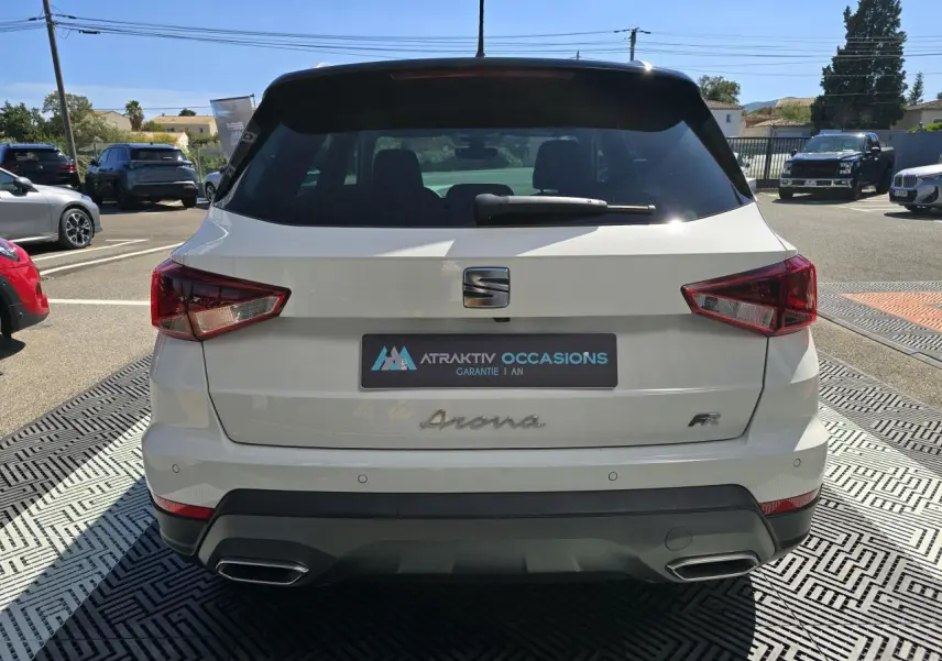 Vue arrière d'un SEAT Arona blanc avec toit noir, badge FR et double sortie d'échappement chromée.