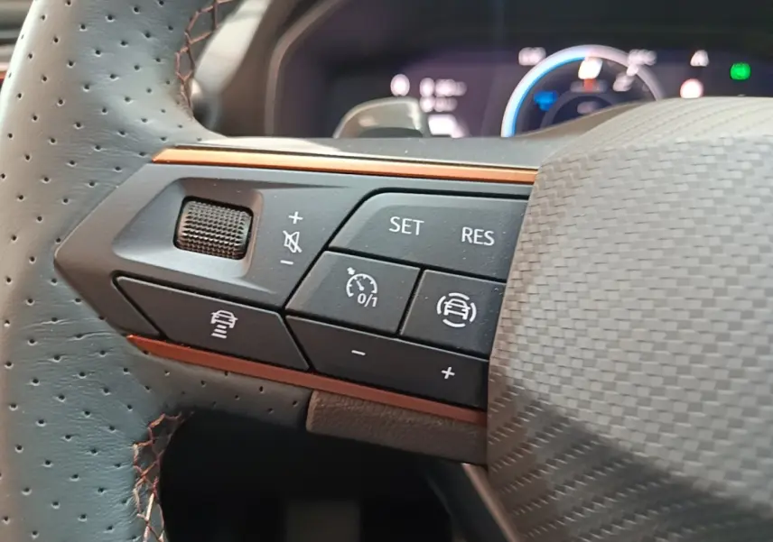 Gros plan sur les commandes gauche du volant perforé noir du CUPRA Formentor 2024 avec surpiqûres orange.