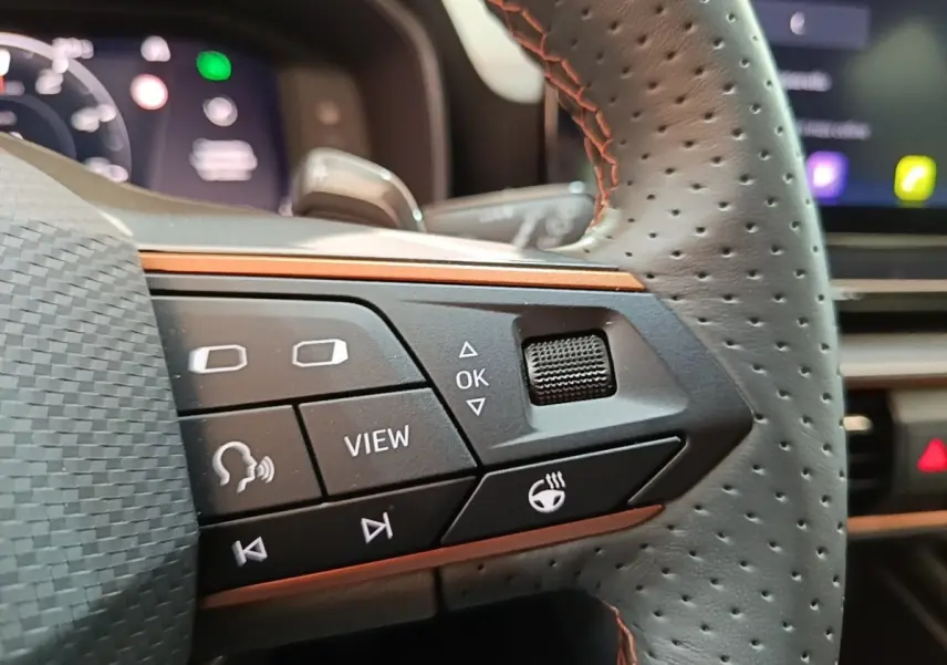 Gros plan sur le volant cuir perforé noir du CUPRA Formentor 2024, avec commandes multifonctions et surpiqûres orange.