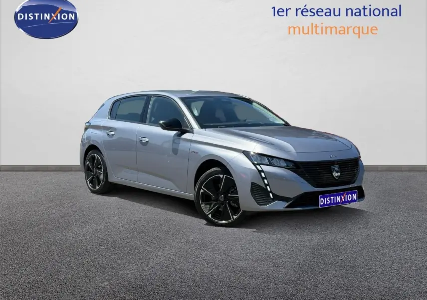 Peugeot e-308 gris Artense en 3/4 avant droit, avec jantes alu noires et signature lumineuse LED verticale.