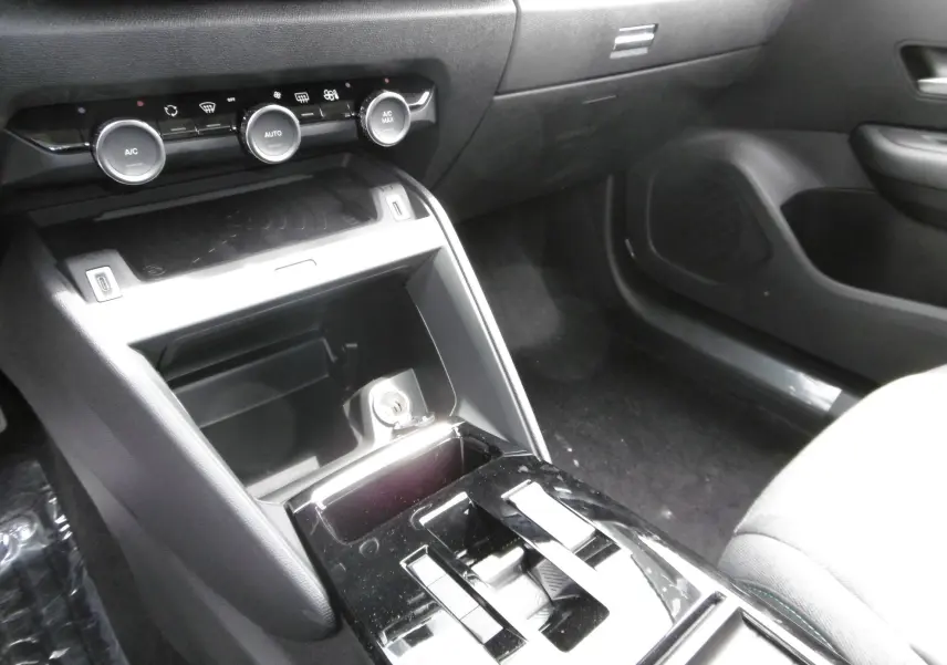 Vue rapprochée de la console centrale noire du Citroën C4 X 2023 avec commandes climatisation et rangement ouvert.