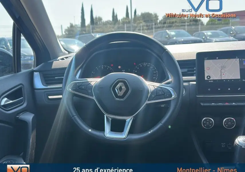 Vue intérieure centrée sur le volant du Renault Captur gris 2022 avec tableau de bord et écran tactile visible.