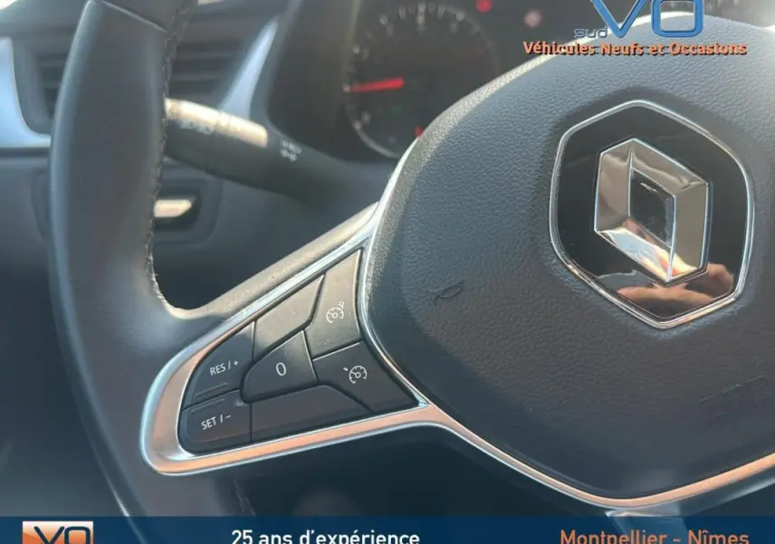 Gros plan sur le volant du Renault Captur gris 2022, mettant en valeur les commandes du régulateur de vitesse.