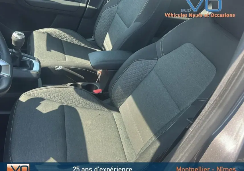 Vue intérieure côté conducteur du Renault Captur gris 2022, montrant les sièges tissu et la boîte manuelle.