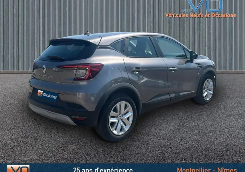 Renault Captur gris 2022 vue 3/4 arrière côté droit sur parking, avec feux arrière et jantes visibles.
