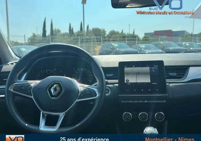 Vue intérieure du tableau de bord du Renault Captur gris 2022 avec écran tactile et volant multifonction.