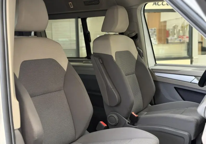 Vue intérieure côté droit des sièges avant gris clair et foncé du Volkswagen California T7 2024, avec accoudoirs et appui lombaire.