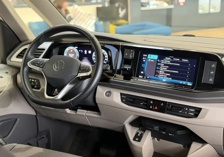 Vue intérieure côté conducteur du tableau de bord beige et noir du Volkswagen California T7 avec volant cuir multifonction.