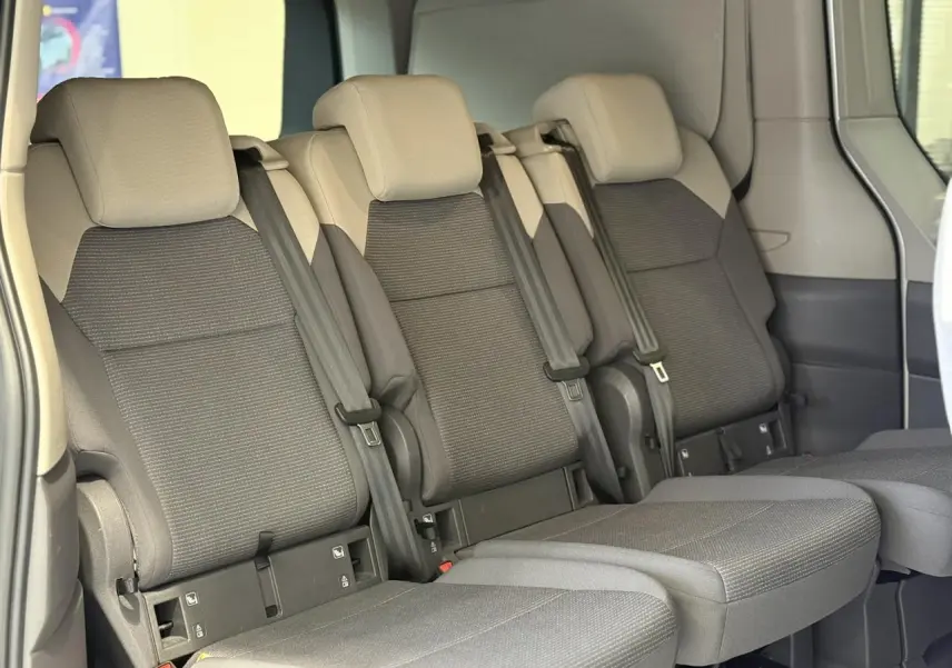 Vue intérieure côté droit des trois sièges arrière gris foncé du Volkswagen California T7 2024 avec ceintures intégrées.