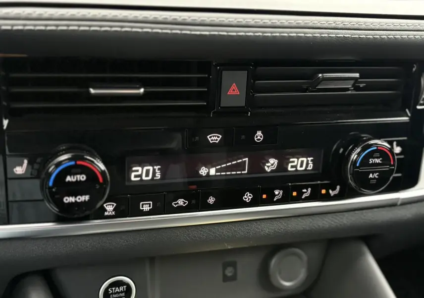 Gros plan sur la console centrale du Nissan Qashqai 2024, affichant la climatisation automatique bi-zone et les commandes chauffantes.